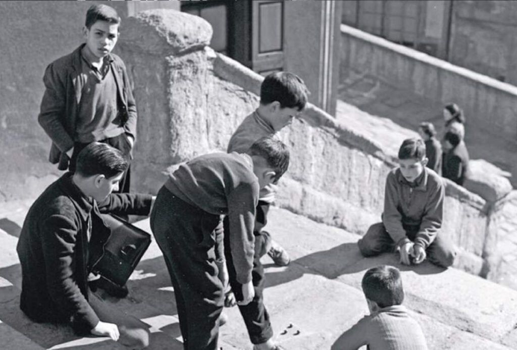 Un grup de nens juguen a bales a les escales de la parròquia, a la plaça de Sant Pere, l'any 1959. | Josep Pons i Tubau